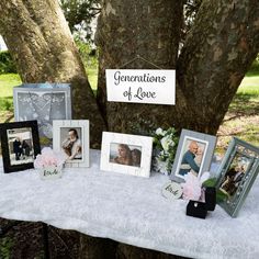 a table topped with pictures and flowers next to a tree