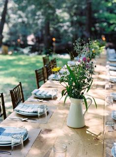 a table set with place settings and flowers in a vase on the centerpieces