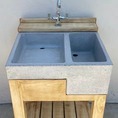 a sink made out of concrete sitting on top of a wooden shelf next to a faucet