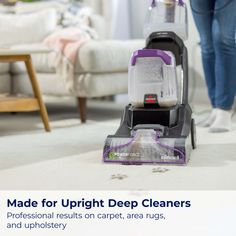 a person vacuuming the floor with a purple and black cleaning machine