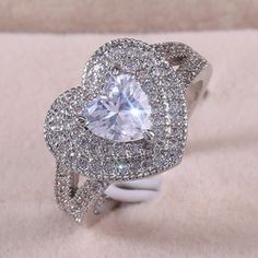 a white gold ring with an oval cut diamond surrounded by pave diamonds