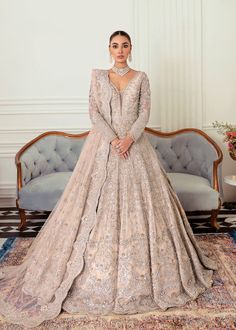 a woman standing in front of a couch wearing a wedding dress