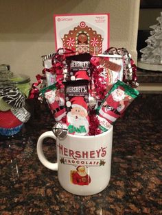 a coffee mug filled with candy and candies on top of a counter next to a christmas tree