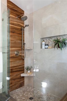 a bathroom with a glass shower door and wooden paneling on the wall behind it