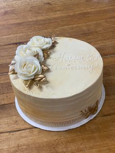 a cake with white frosting and flowers on it sitting on a wooden table top