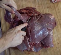 a person cutting up meat on top of a wooden table