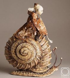 a figurine that is sitting on top of a snail's shell,