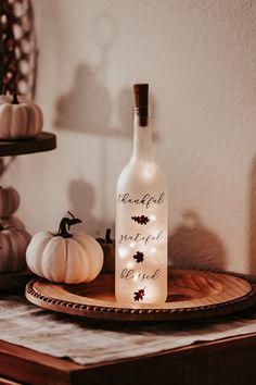 a bottle with some lights in it sitting on a table next to pumpkins and other decorations