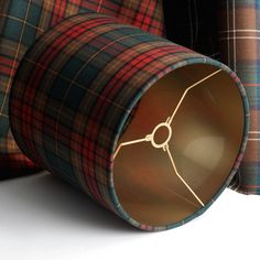 three different colored tartan plaid fabric wrapped around the bottom of a tube, one with gold thread on it