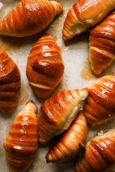 many croissants are lined up on a sheet of wax paper and placed next to each other