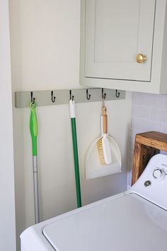 a white washer sitting next to a dryer in a bathroom under a cabinet