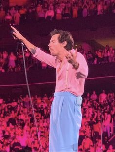 a man standing on top of a stage holding a microphone in front of an audience