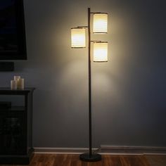 a lamp that is on top of a wooden floor in a room with a tv