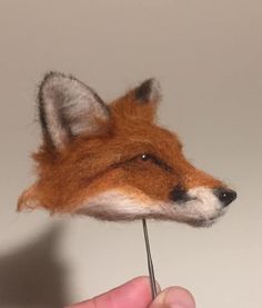 a needle - felt fox head being held by a hand