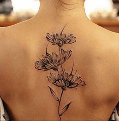 the back of a woman's neck with flowers tattooed on her upper and lower back