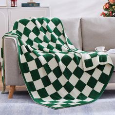 a green and white blanket sitting on top of a couch next to a christmas tree