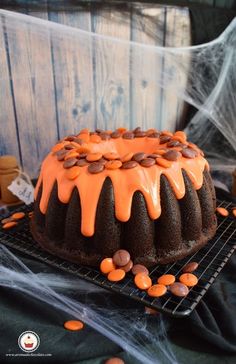 a bundt cake with orange icing and chocolate chips on a wire cooling rack