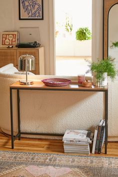 a living room with a couch, mirror and plant on the table in front of it