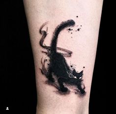 a black and white cat tattoo on the right leg, with ink splatters all over it