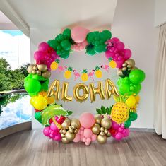 a balloon arch with the word aloha spelled out in gold letters and pineapples