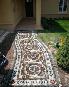 a walkway made out of mosaic tiles in front of a house