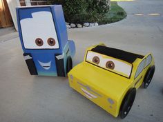 two cardboard cars sitting on top of a cement floor next to each other in front of a house