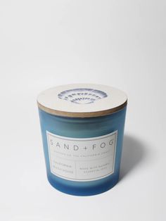 a blue candle with a white lid on a white surface, in front of a white background