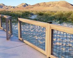 a wooden and metal fence next to a body of water with mountains in the background