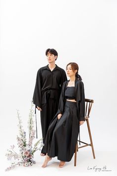 two people standing next to each other in black outfits