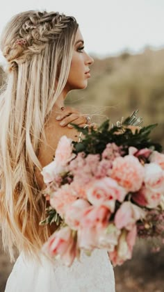 a woman holding a bouquet of flowers in her hand and looking off into the distance