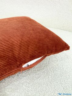 an orange corded pillow sitting on the floor