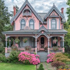 a pink house with flowers in the front yard