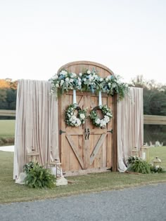 a wooden door decorated with white flowers and greenery sits in front of a backdrop