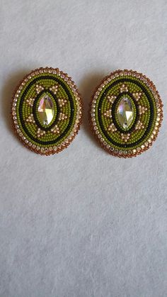 pair of green and gold beaded earrings on white tablecloth with small circular design