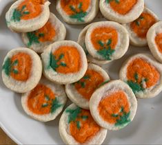 small cookies decorated with green and orange icing on a white plate