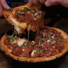 a person taking a slice of deep dish pizza