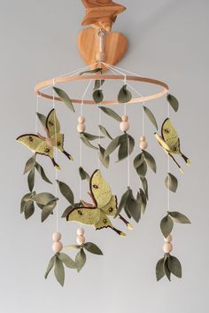 a mobile with green leaves and butterflies hanging from it