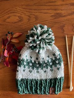 a green and white knitted hat next to chopsticks on a wooden table