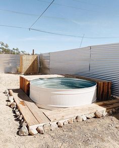 an outdoor hot tub sitting on top of a wooden pallet next to a fence