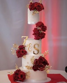 a three tiered wedding cake with red roses on top and the number twenty seven