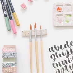 some art supplies are laying out on a white surface with markers, pens and washi tape