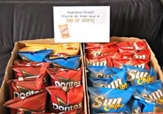 a cardboard box filled with chips sitting on top of a black couch next to a sign that says, you're all that and a bag of chips