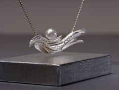 "A lustruous white pearl rests atop three sterling silver \"branches\". Each branch is hand-forged, starting with a flat sheet of sterling which is wrapped around itself, to form a hollow shape. The technique I use to shape the silver, called anticlastic raising, gives strength to the metal, while allowing the pendant to remain light-weight, despite its size. The branches are soldered together. The pearl is securely epoxied on a silver peg soldered onto the body of the pendant. The pearl is a na Elegant Hand-cast Pendant Jewelry, Elegant Silver Hand Forged Necklaces, Unique Silver Pearl Drop Necklace, Elegant Hand-cast Jewelry, Elegant Hand Cast Pendant Jewelry, Elegant Hand Cast Necklaces For Anniversary, Elegant Hand Cast Necklace For Anniversary, Elegant Hand-cast Pendant Necklace, Elegant Handmade Pendant Necklace