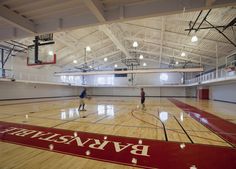 two men are playing basketball in an indoor gym with hard wood floors and white walls