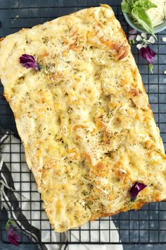 a piece of bread on a cooling rack next to some flowers and lettuce