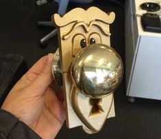 a hand holding a metal object with a face on it's head and an eyeball in the middle