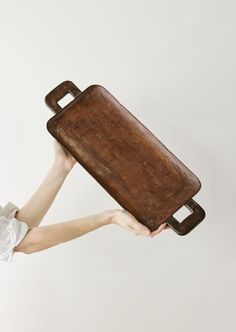 a person holding up a wooden tray with handles