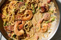 a pan filled with pasta and shrimp on top of a stove