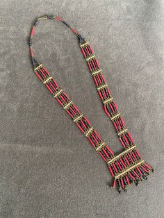 Beautiful Ethnographic Coral red tone and brass tribal inspired necklace with multiple bead strands hanging from etched brass bars. Beautiful craftsman quality look. Tribal / tropical / boho chic. Casual style but very pretty. Bohemian Multi-strand Brass Necklaces, Traditional Brass Jewelry With Colorful Beads, Artisan Red Beaded Necklace With Dangling Beads, Red Bohemian Dangling Beads, Red Fair Trade Necklace For Festival, Red Bohemian Fair Trade Necklace, Festive Bohemian Wooden Beads Jewelry, Traditional Multi-strand Wooden Bead Necklaces, Traditional Brass Beaded Necklaces For Festivals