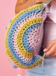 a woman is holding a crocheted purse